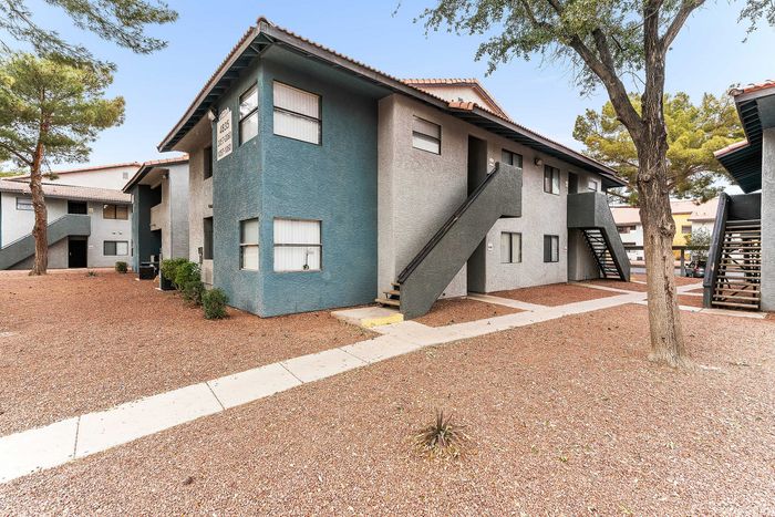 Charming desert-style apartment complex with modern two-toned facade and outdoor staircase surrounded by landscaped grounds.