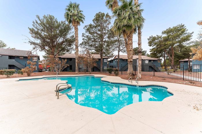 Inviting outdoor pool area surrounded by lush palm trees, offering a relaxing oasis in a vibrant residential community.