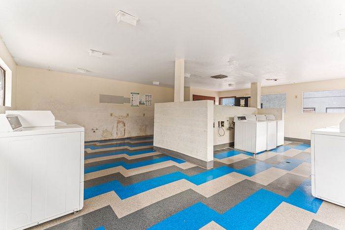 Bright and spacious laundry room featuring modern white machines and bold geometric flooring design.