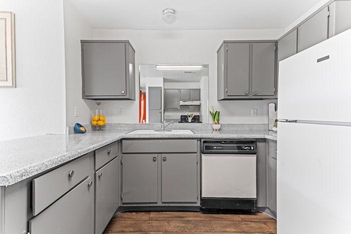 Modern kitchen with sleek gray cabinets, granite countertops, and stylish appliances. Bright, open space accented with fresh orange decor.