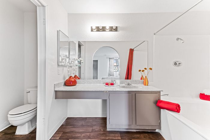 Modern bathroom with sleek fixtures, elegant countertop, and vibrant red accents, creating a stylish and inviting space.