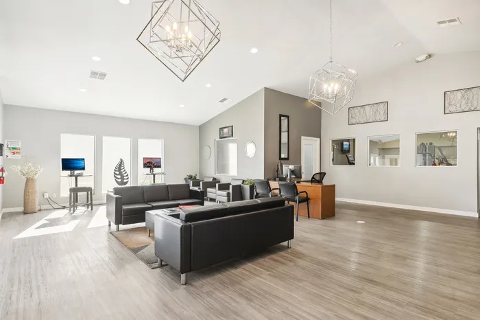 Modern, sunlit office space featuring sleek black leather seating and stylish geometric light fixtures.