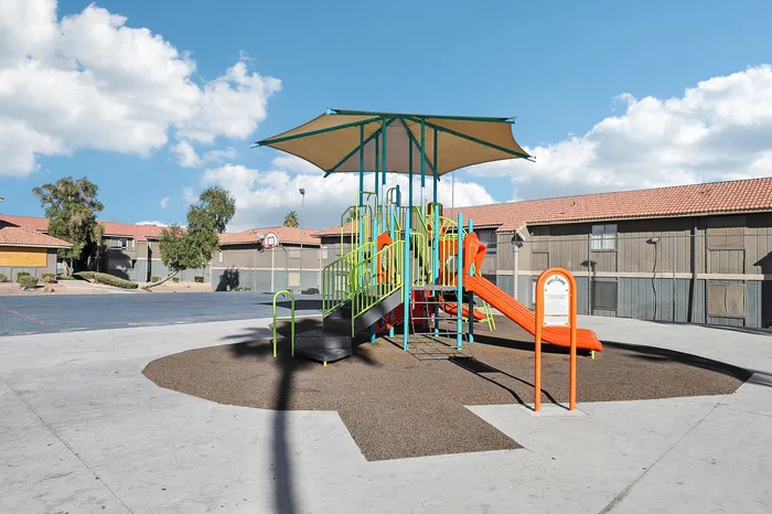 Charming community playground with colorful slides and shaded seating, surrounded by well-maintained apartments and scenic views.
