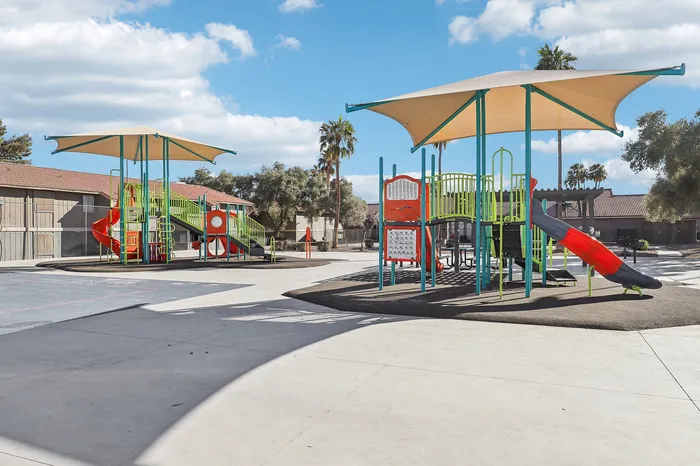 Inviting playground with vibrant slides and climbing structures, surrounded by sunny palm trees and picturesque sky.