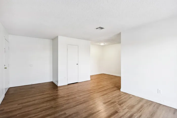 Bright and airy living space with elegant wood flooring, crisp white walls, and modern recessed lighting.