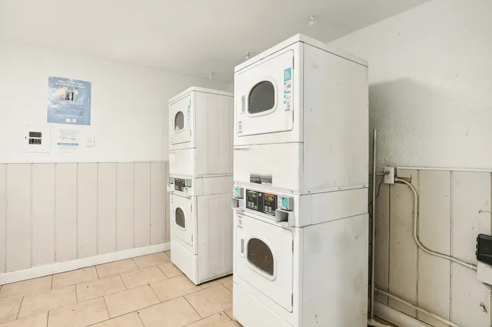 Bright and convenient laundry room featuring modern stacked washers and dryers, perfect for effortless living.