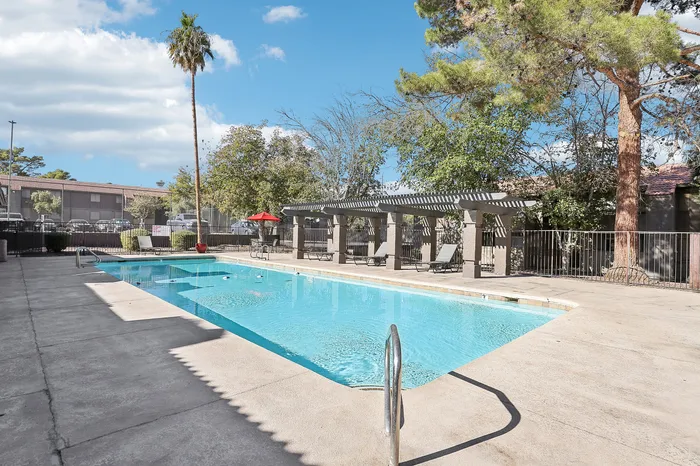 Inviting outdoor pool surrounded by lush greenery and stylish pergolas, offering a perfect relaxing retreat.