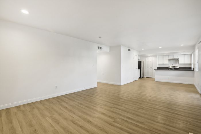 Bright and spacious open-concept living area with modern hardwood flooring and a sleek kitchen layout, perfect for entertaining.