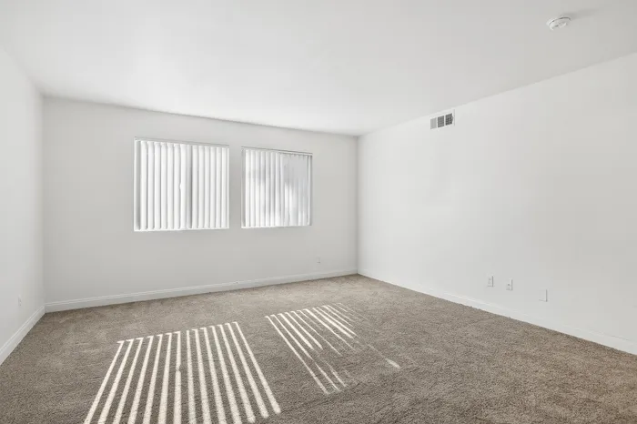 Bright and airy room with plush carpet and large windows, perfect for a relaxing bedroom setup.