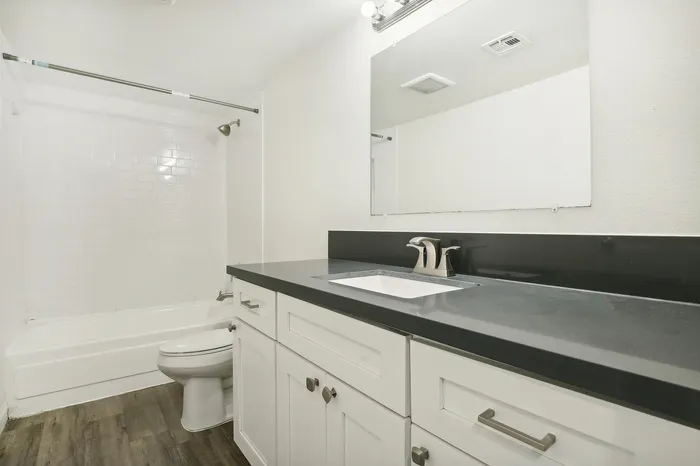 Elegant bathroom with modern white vanity, sleek countertop, and pristine subway tile shower.