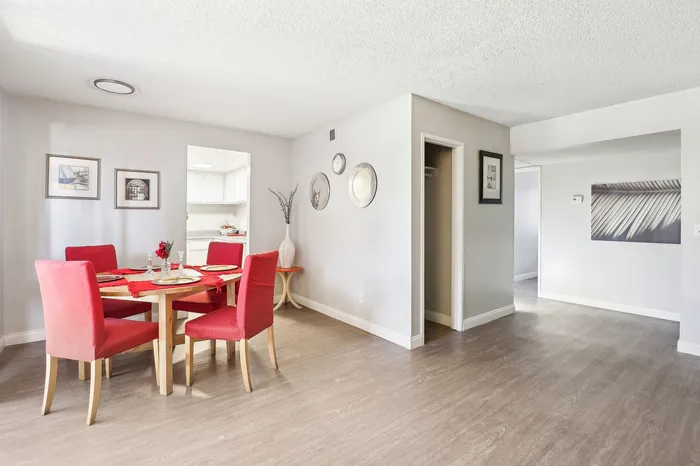 Bright dining area with stylish red chairs, modern decor, and an inviting open layout leading to the kitchen.