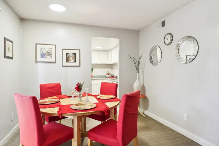 Elegant dining area with red cushioned chairs, a wooden table adorned with vibrant decor, and wall art creating a chic ambiance.