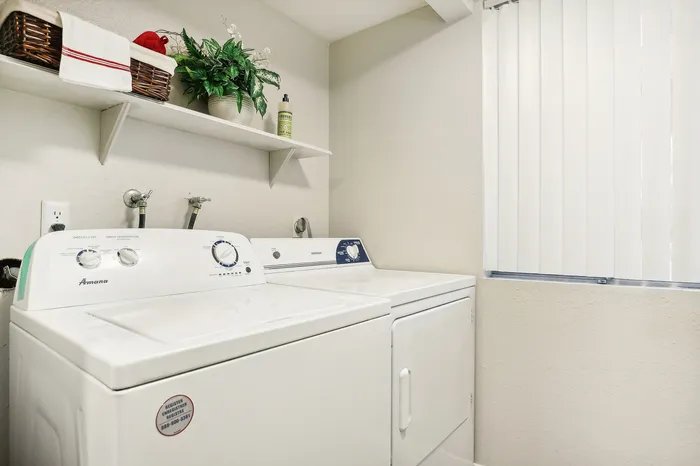 Bright laundry room with modern washer and dryer, stylish shelving, and ample natural light.