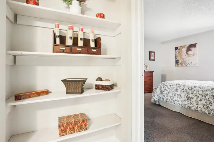 Charming bedroom view with cozy bookshelf, elegant floral bedding, and tasteful artwork, offering a serene and stylish living space.