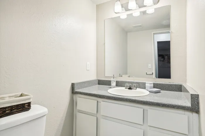 Modern bathroom showcasing a sleek countertop, large mirror, and elegant lighting for a fresh and inviting space.