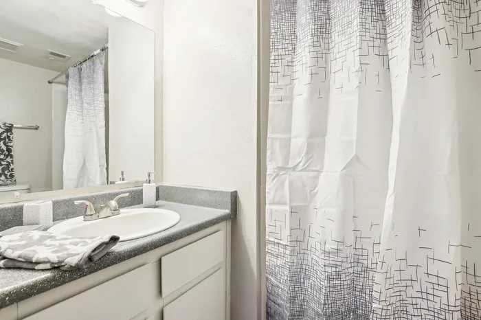 Chic bathroom with modern sink, stylish gray countertop, and contemporary geometric shower curtain.