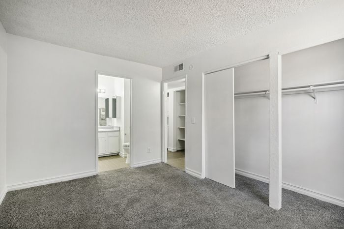 Bright and airy bedroom with plush carpet, built-in closet, and en-suite bathroom featuring modern fixtures.