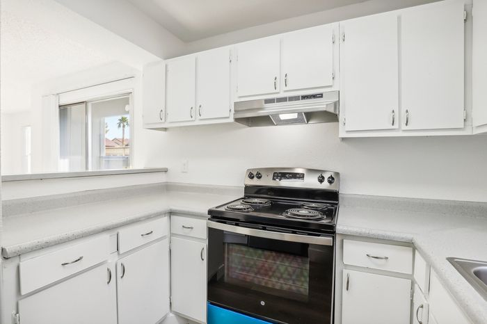 Modern kitchen with sleek white cabinets, stainless steel stove, and a spacious countertop, offering a bright, inviting atmosphere.