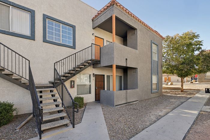 Charming two-story apartment exterior with modern design, featuring a welcoming balcony and convenient stair access.