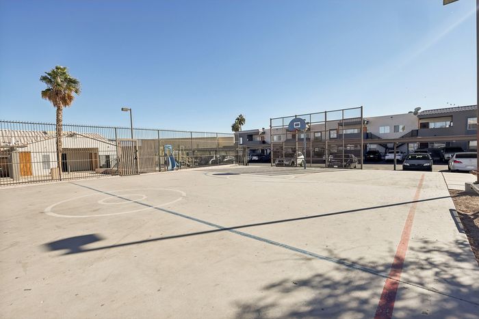 Vibrant outdoor basketball court with a sunny backdrop, ideal for sports enthusiasts, located in a modern apartment complex.