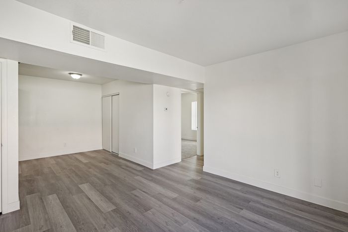 Bright and airy living space featuring elegant wood flooring and neutral walls, offering a spacious and open feel.