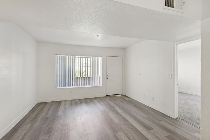 Bright and inviting living space with large window, sleek flooring, and modern minimalist design.