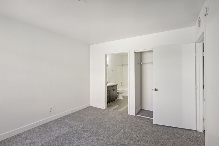 Bright and airy bedroom with plush carpeting, convenient closet space, and an en-suite bathroom.