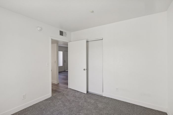 Inviting apartment bedroom with fresh white walls, cozy gray carpet, and natural light creating a serene atmosphere.