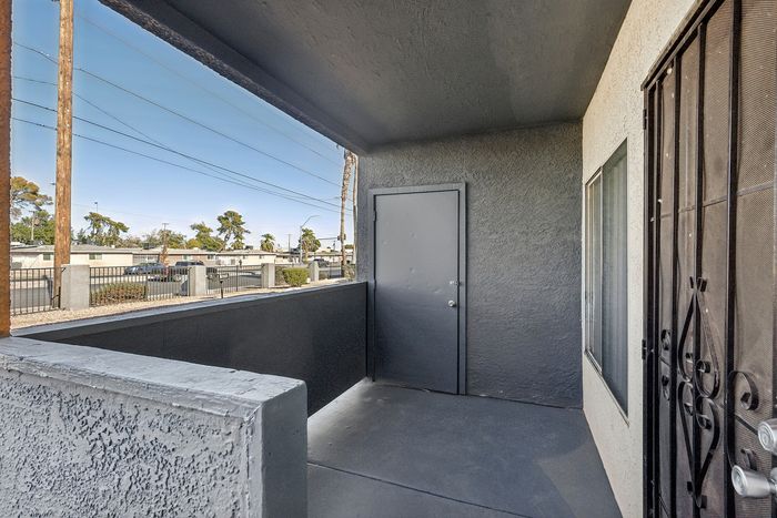 Charming balcony space with sleek walls and a contemporary door, perfect for morning coffee or unwinding outdoors.