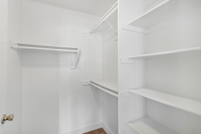 Bright and spacious walk-in closet with ample shelving and hanging rods, ideal for organizing your wardrobe efficiently.
