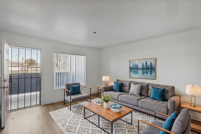 Bright and inviting living room with modern gray sofas, decorative cushions, and a cozy area rug, perfect for relaxation and entertainment.