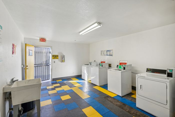 Bright and functional laundry room with colorful tiled floor, equipped with modern washers and dryers for convenient living.