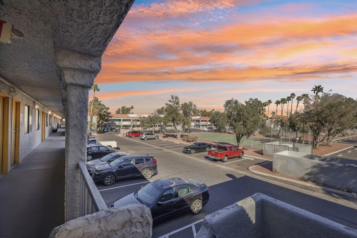 Charming apartment view showcasing vibrant sunset skies, palm trees, and ample parking space.