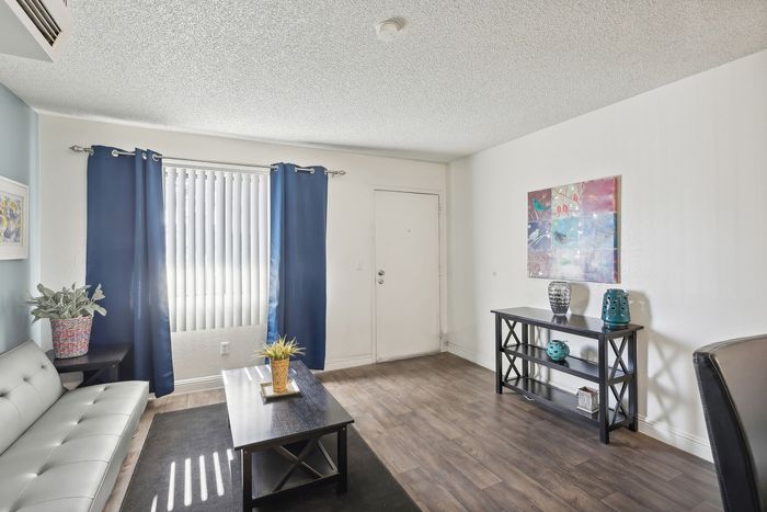 Bright and inviting living room with stylish gray sofa, sleek wooden flooring, and vibrant decor, perfect for relaxation and entertaining.