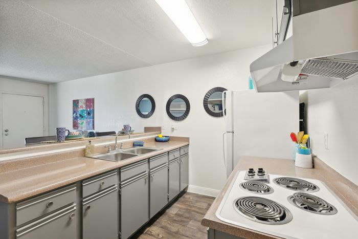 Modern kitchen with sleek countertops, contemporary cabinets, and stylish appliances, enhanced by decorative wall mirrors and vibrant decor for a welcoming atmosphere.