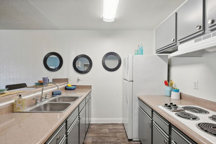 Modern kitchen with sleek countertops, dual sinks, and stylish mirrors, featuring contemporary cabinetry and a spacious fridge.
