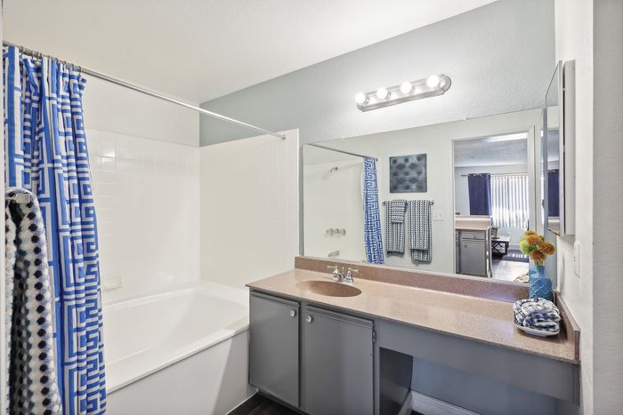Contemporary bathroom with elegant features, including a chic vanity, large mirror, and inviting bathtub, highlighted by stylish blue accents.