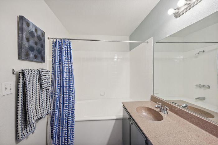 Bright and modern bathroom featuring a sleek countertop, stylish blue geometric shower curtain, and elegant lighting.