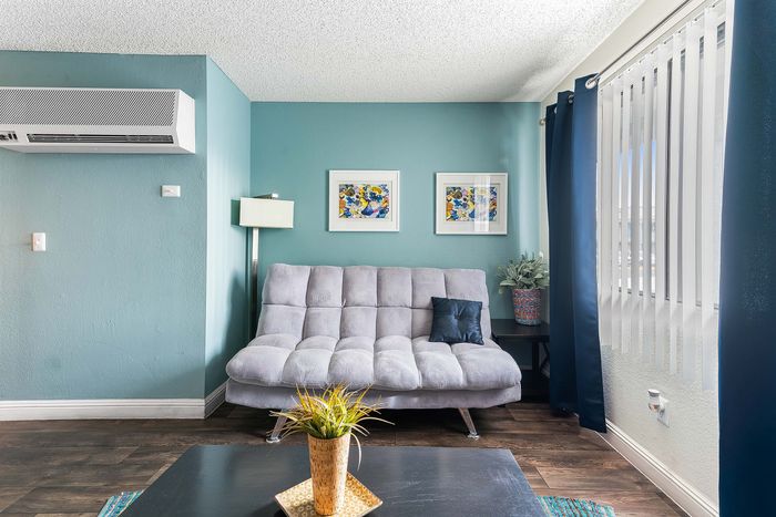 Inviting living space with a cozy gray sofa, colorful artwork, and vibrant green accents against soothing teal walls.
