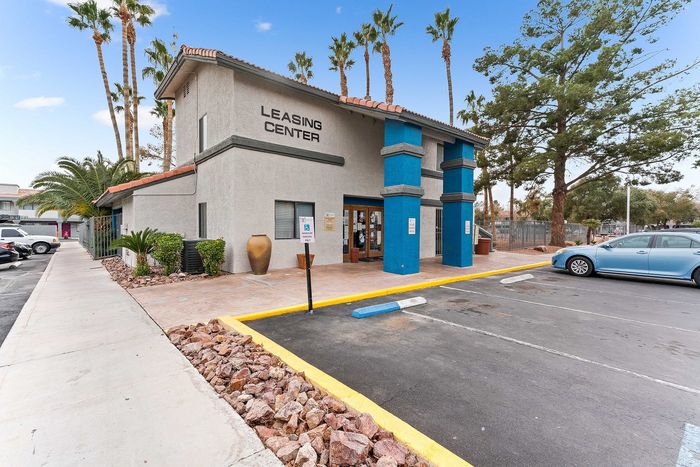 Inviting leasing center with modern architecture, surrounded by lush palm trees and ample parking space.