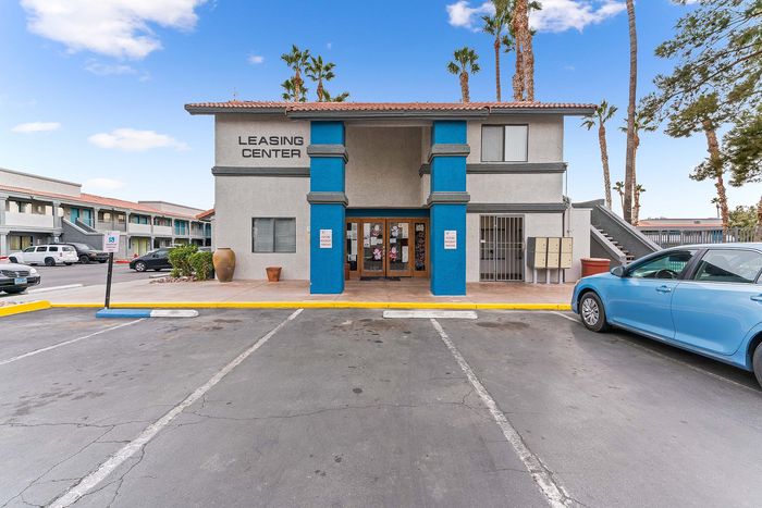 Inviting leasing center exterior with vibrant blue accents and palm trees, offering a welcoming atmosphere for prospective tenants.