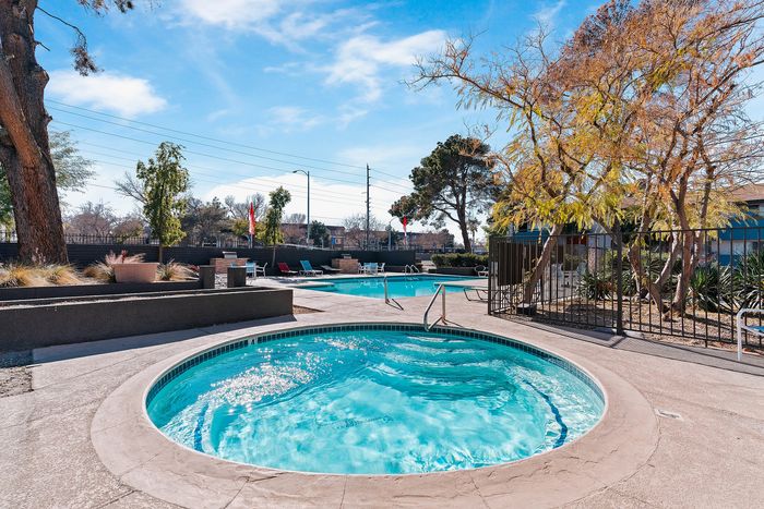 Inviting outdoor pool area with sparkling blue water, surrounded by lush trees and stylish lounge chairs, perfect for relaxation and leisure.