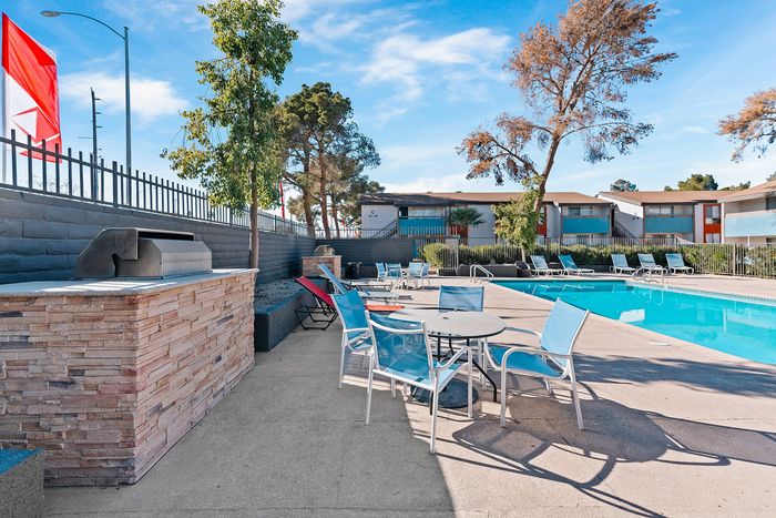Inviting outdoor area featuring a sparkling swimming pool, stylish lounge chairs, and a modern BBQ setup surrounded by lush greenery.
