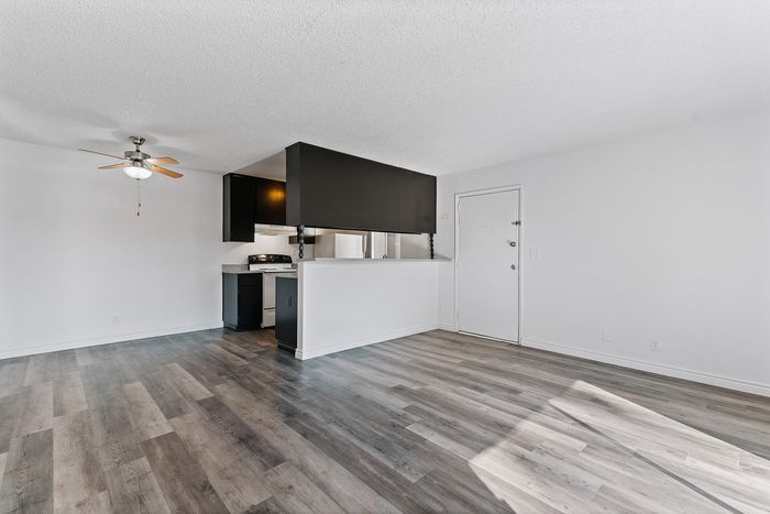 Bright open-plan apartment featuring a sleek kitchen, inviting ceiling fan, stylish flooring, and ample natural light.
