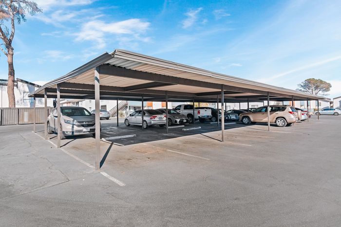 Modern covered parking area with multiple parked vehicles under a bright blue sky, enhancing convenience and protection.