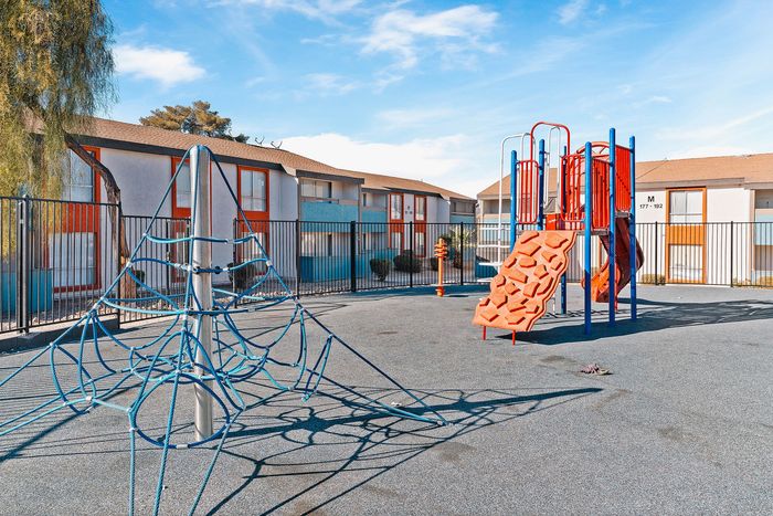 Inviting apartment complex featuring a colorful playground with climbing structures, perfect for family-friendly living.