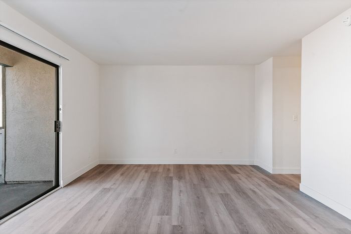 Bright and spacious room featuring elegant wooden flooring and a large sliding glass door offering ample natural light.