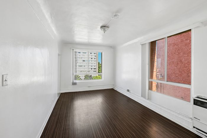 Bright, airy room with large windows and sleek wooden flooring, showcasing a modern, minimalist style.