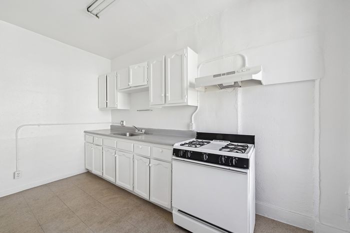 Bright, minimalist kitchen with sleek white cabinetry and modern gas stove, perfect for culinary creativity.