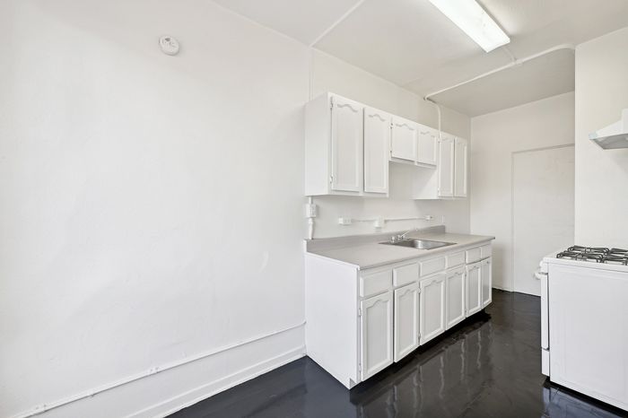 Bright, modern kitchen with sleek white cabinetry and polished black flooring.